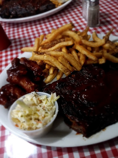 BBQ rib plate with fries and coleslaw on a red checkered tablecloth